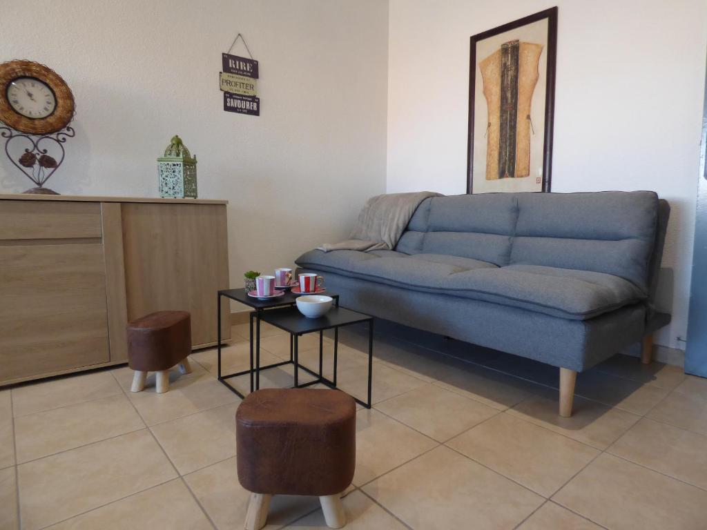 uma sala de estar com um sofá azul e uma mesa em Appartement T2 coquet, proche mer, Narbonne Plage em Narbonne Plage