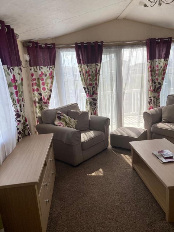 a living room with couches and a couch and curtains at Skegness B10 in Chapel Saint Leonards