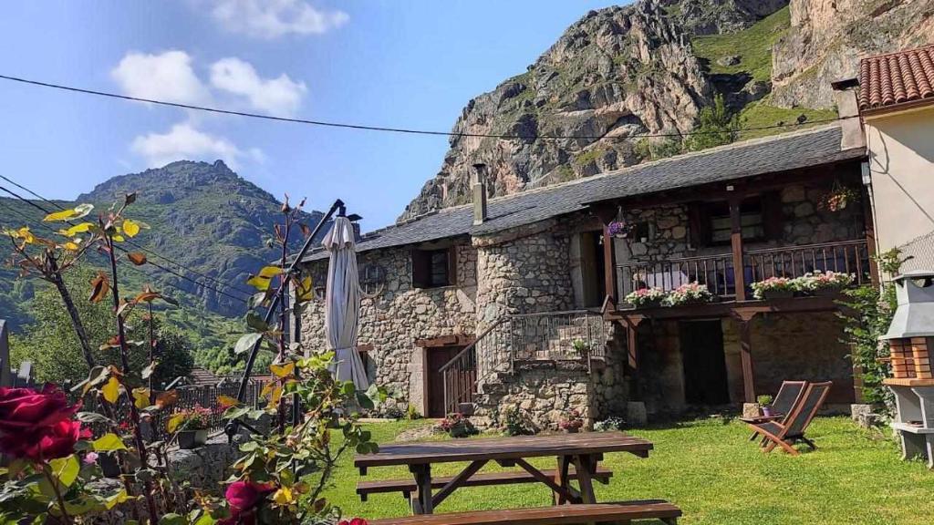 un edificio de piedra con una mesa de picnic delante de él en Apartamentos Rurales La Laguna Somiedo, en Valle de Lago