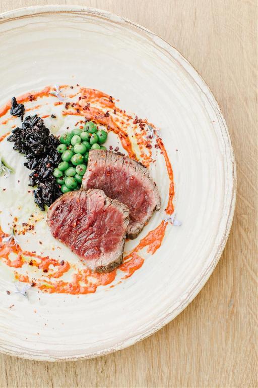 a plate of food with meat and peas on it at Hôtel Restaurant Les Arnelles in Saintes-Maries-de-la-Mer