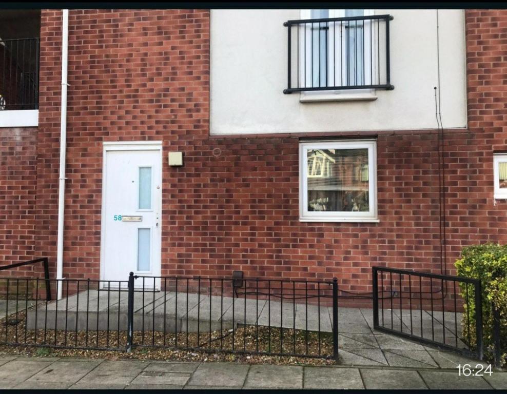 a brick building with a white door and a fence at Immaculate 1-Bed Apartment in Stoke-on-Trent in Stoke on Trent