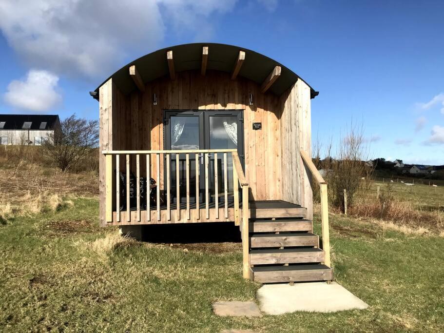 a wooden out house with a staircase in the grass at The Coach House in Orbost