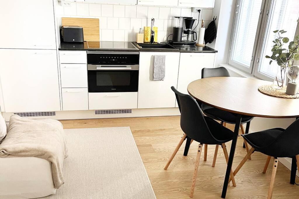 uma cozinha com uma mesa e uma mesa e cadeiras em Ihana huoneisto Turun Kakolassa em Turku