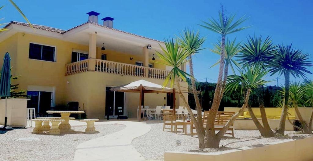 a yellow house with palm trees in front of it at Stunning 3 bedroom villa near Pinoso 