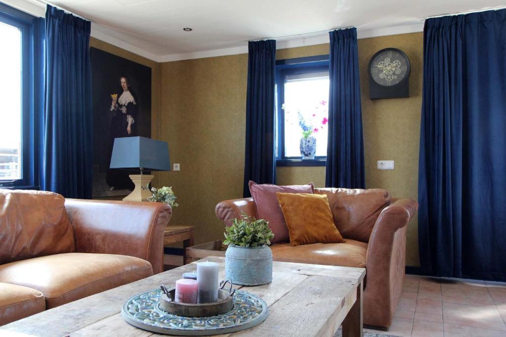 a living room with leather couches and a table at Oud-Hollands Huus - Vakantiehuisje Veluwe in Ede