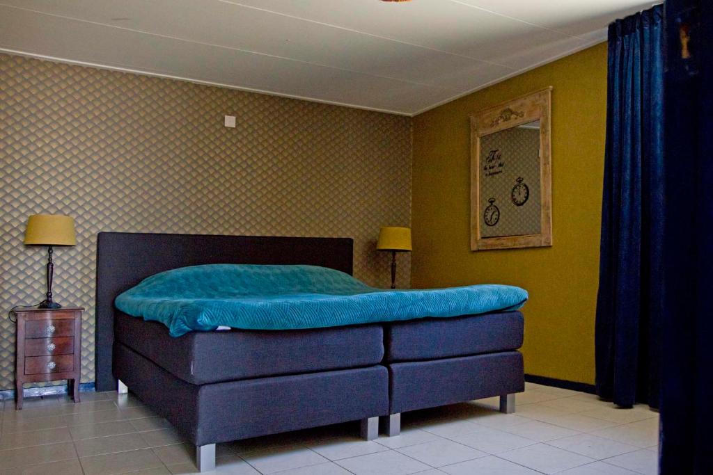 een slaapkamer met een bed met een blauwe deken bij Oud-Hollands Huus - Vakantiehuisje Veluwe in Ede