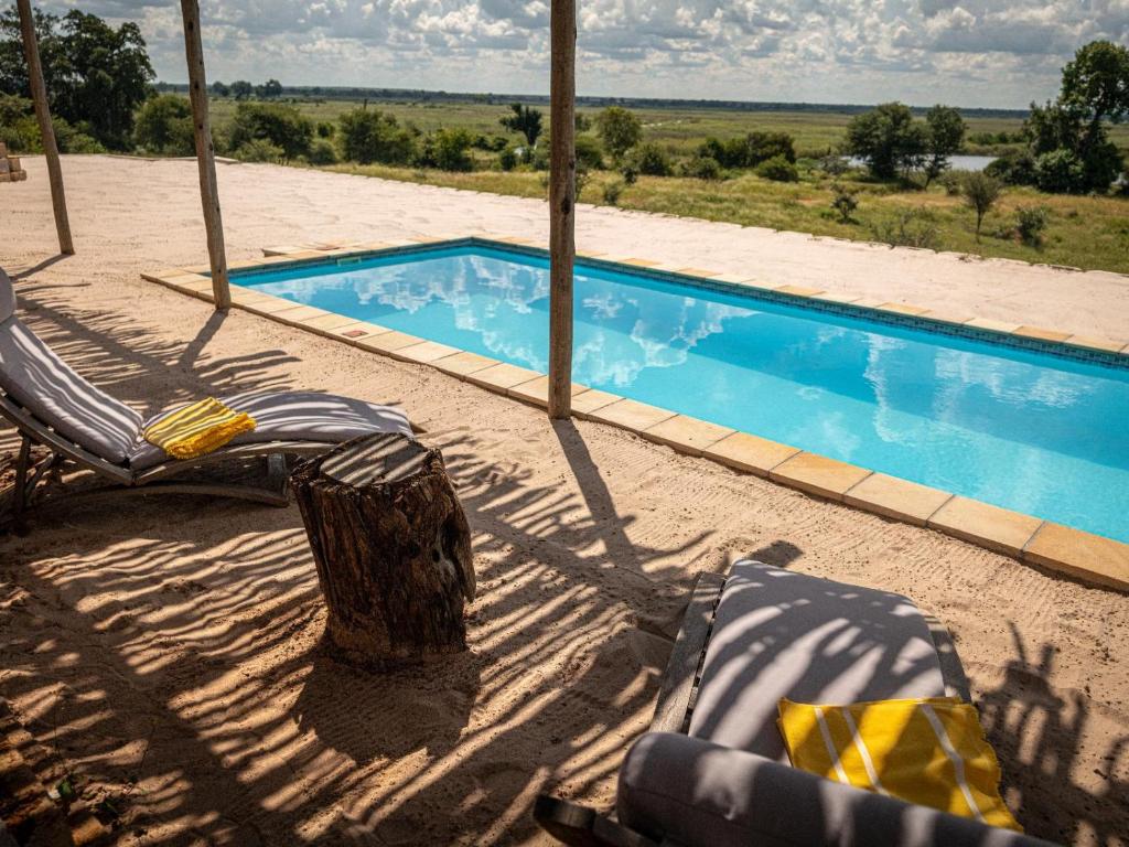 a swimming pool with two lounge chairs in front of it at Kazondwe Camp and Lodge in Kongola