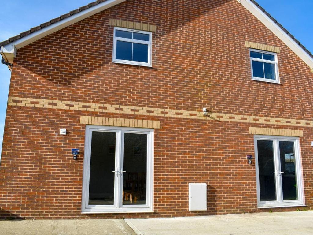 a red brick building with two windows and a door at St Catherines in Porchfield