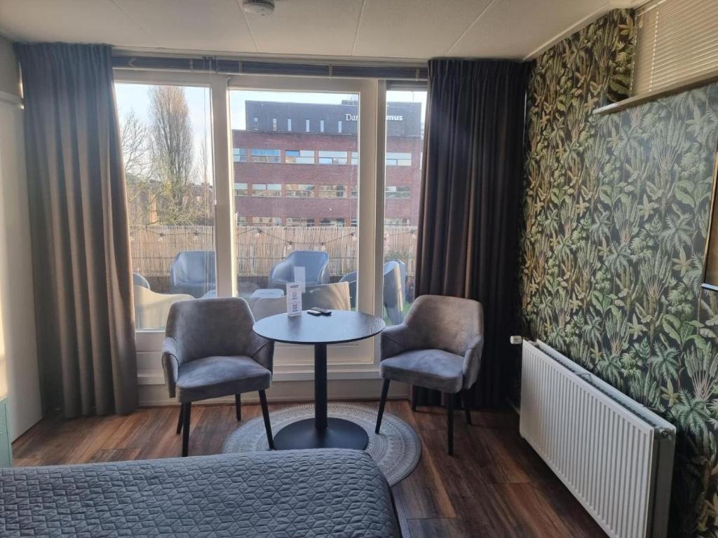 um quarto com uma mesa e cadeiras e uma janela em The Jungle - duo studio with kingsize terrace em Groningen