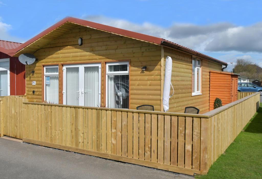 ein Blockhaus mit einem Holzzaun in der Unterkunft Pet friendly sleeps 6 Chalet Bridlington free elec in Bridlington