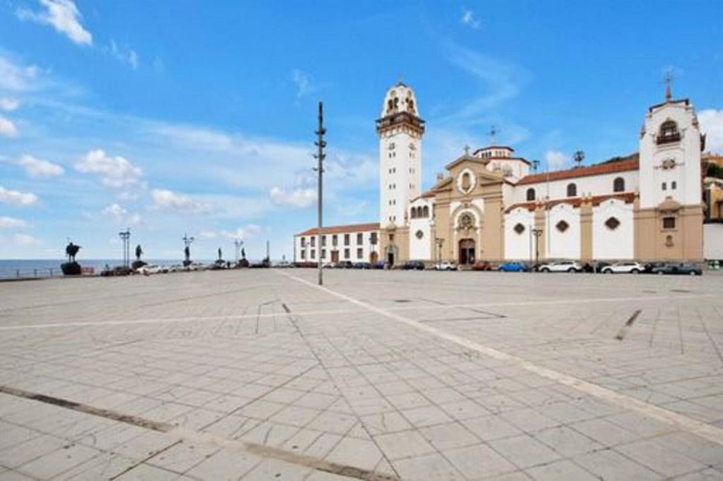 a large building with a clock tower next to the ocean at Impeccable 3-Bedroom El Unicornio Paula in Candelaria