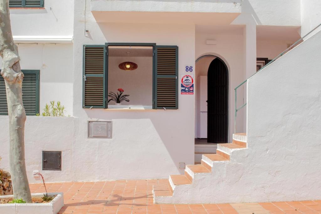 a white house with stairs and a black door at Poblat 86 in Cala Blanca