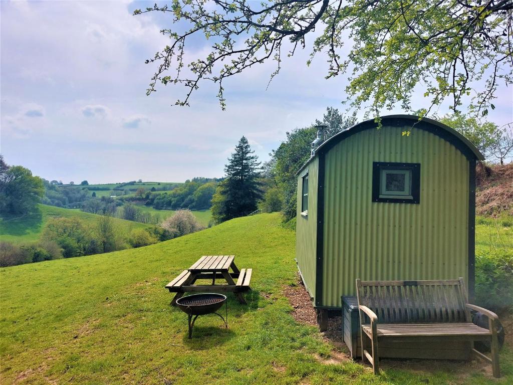 un cobertizo verde con una mesa de picnic y un banco en Usk Valley Shepherd's Hut en Cwmbran