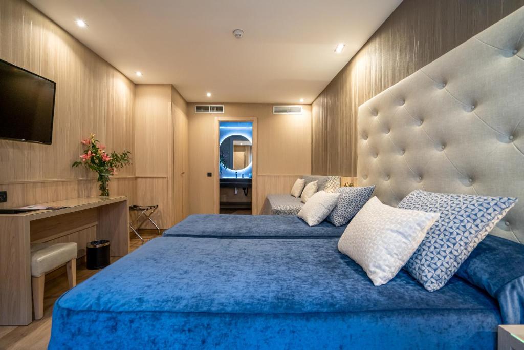 a bedroom with a large blue bed and a television at Hotel Rialto in Barcelona