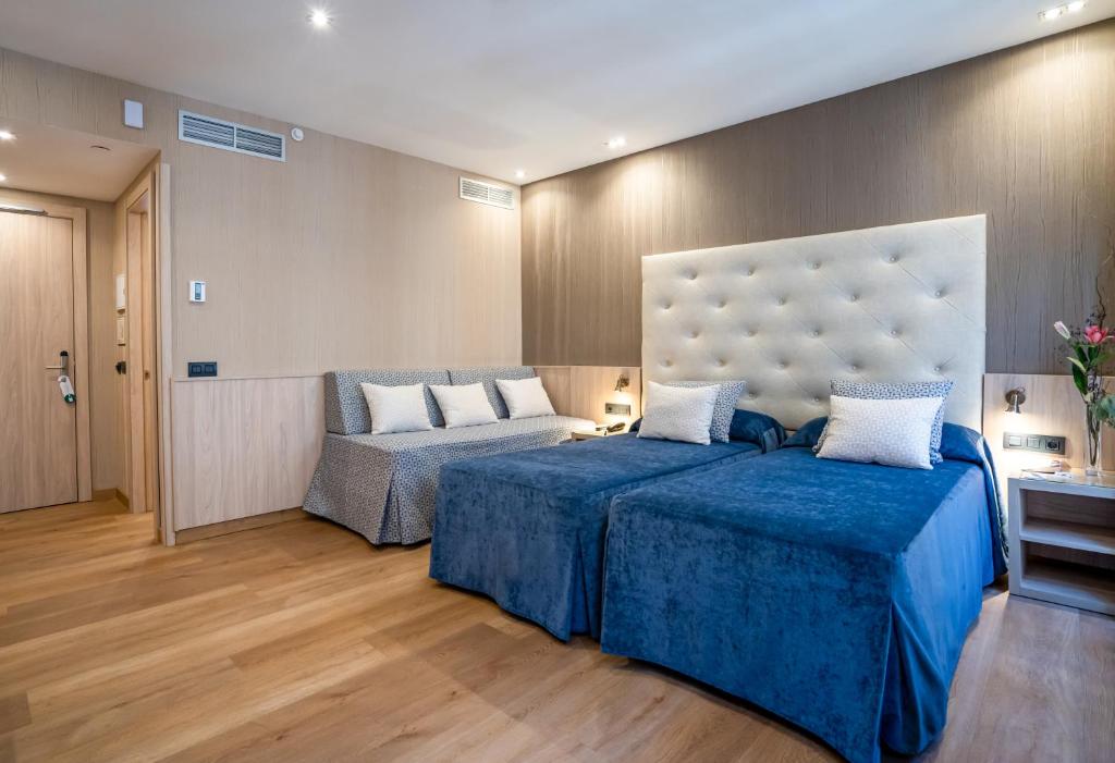 a hotel room with two beds and a couch at Hotel Rialto in Barcelona