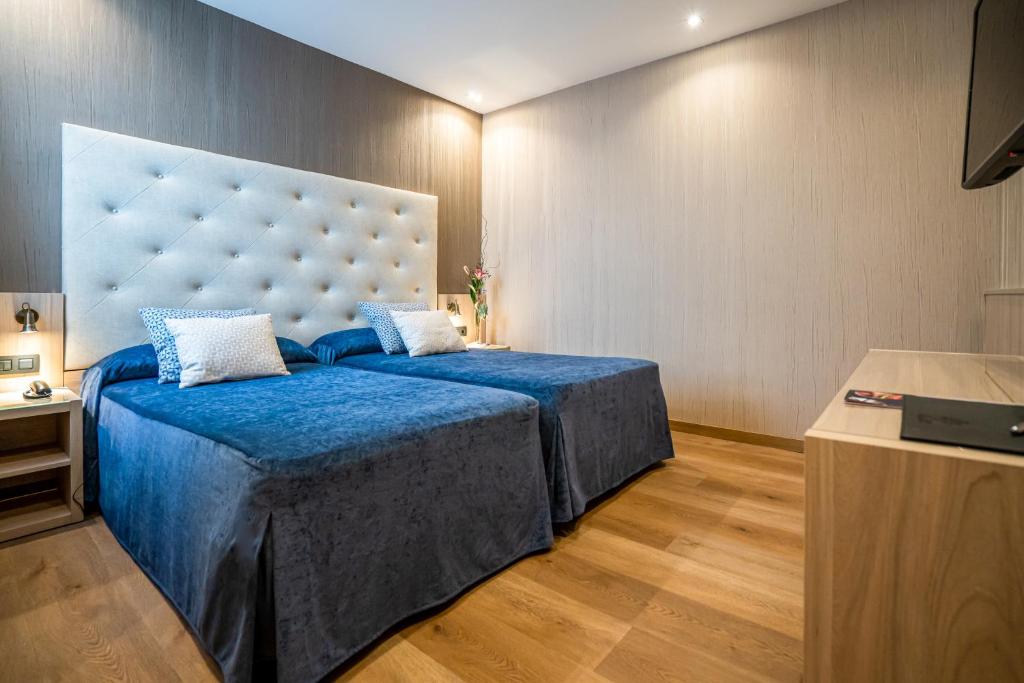 a bedroom with a blue bed with a large headboard at Hotel Rialto in Barcelona