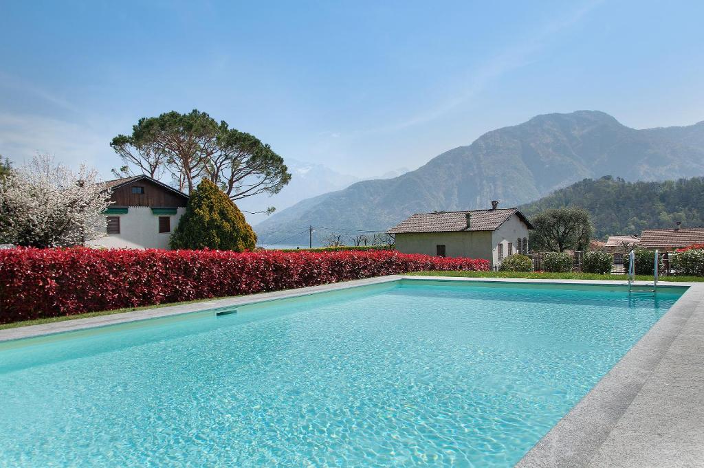 a swimming pool in front of a house with mountains at Appartamento Zerboni C2 in Lenno