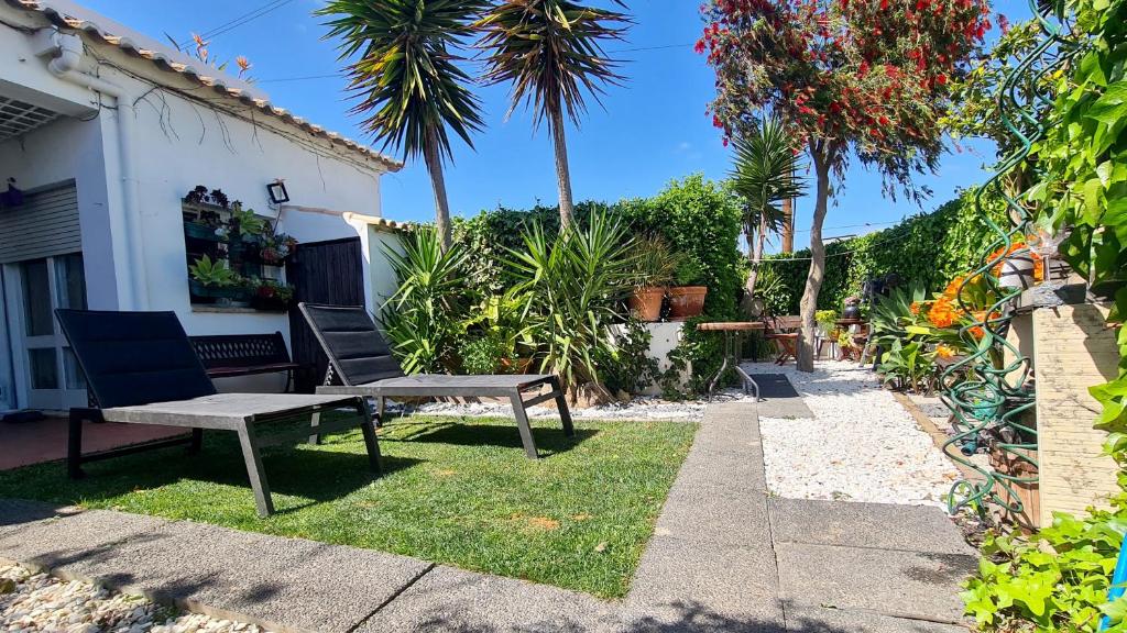 eine Bank und zwei Stühle im Hof eines Hauses in der Unterkunft Cozy Garden T1 near the beach in Albufeira