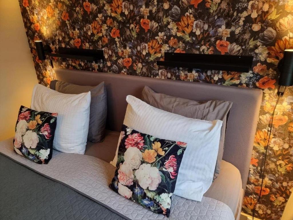 a couch with pillows on it with a floral wall at The Hogg House - a city delight for two in Groningen