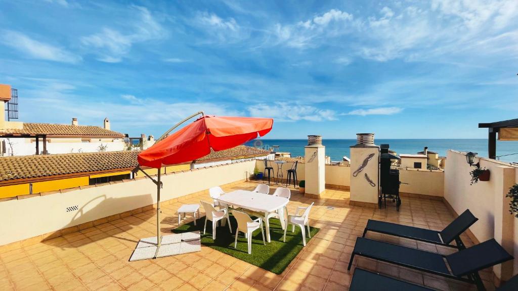 une terrasse avec un parasol, une table et des chaises dans l'établissement Tropical penthouse, à Rincón de la Victoria