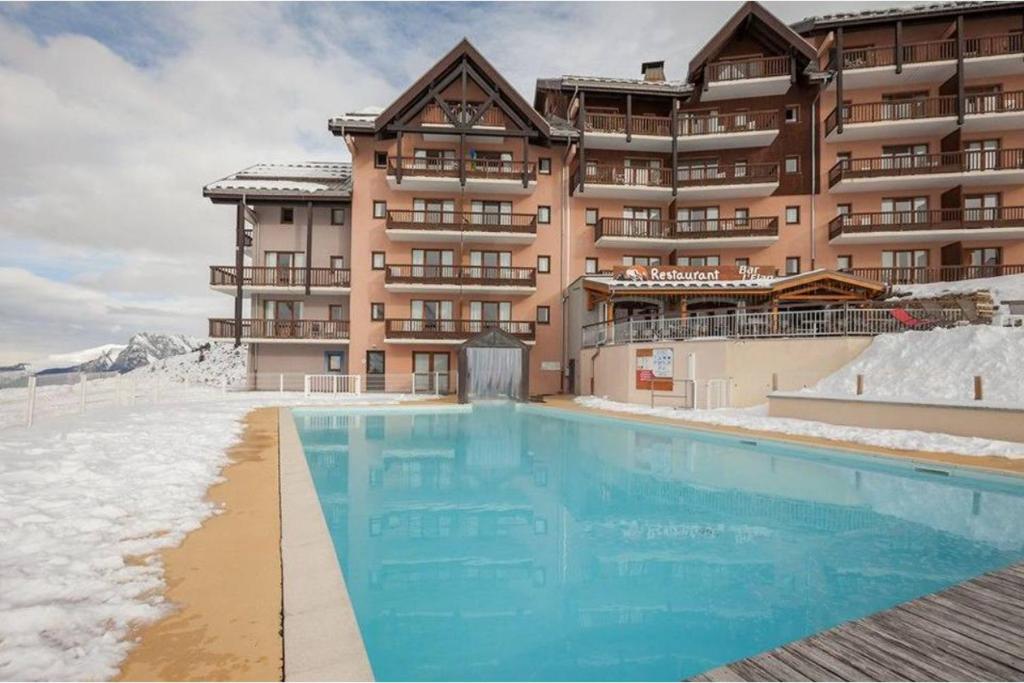 a hotel with a swimming pool in front of a building at Appartement aux pieds des pistes in Valmeinier