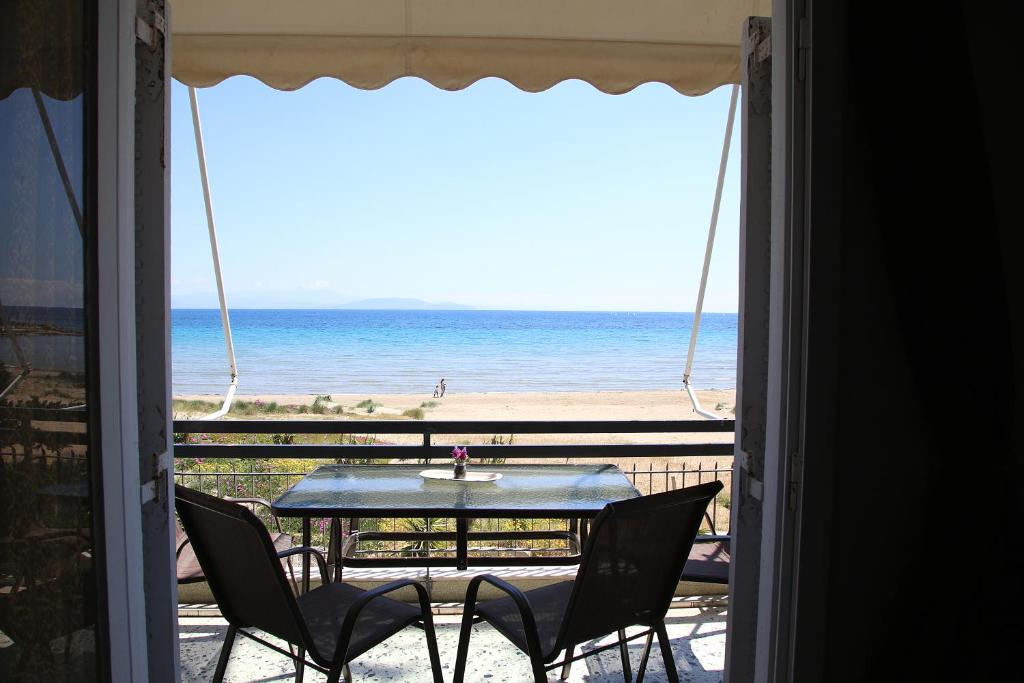 een tafel en stoelen op een balkon met uitzicht op het strand bij Nami Sea View Near Airport Apartment in Artemida