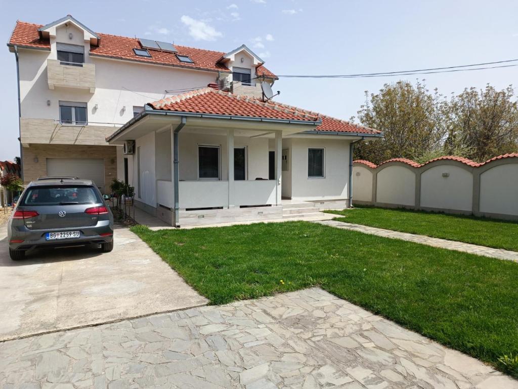 ein Auto, das vor einem weißen Haus parkt in der Unterkunft Serbian home with garden in Krnjača