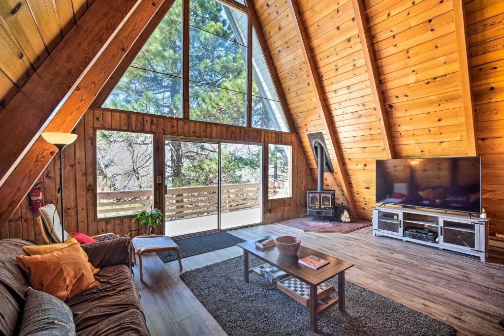 a living room with a couch and a tv in a cabin at Running Springs Cabin with Large Deck and View! in Running Springs