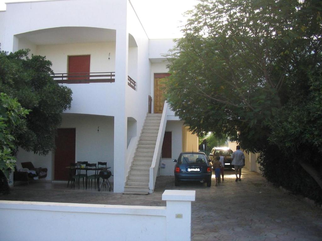 un'auto parcheggiata di fronte a una casa bianca di Appartamenti Alba e Tramonto a Marina di Mancaversa