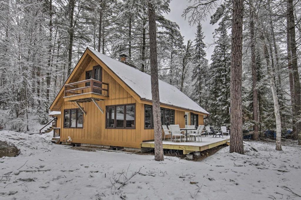 a wooden cabin in the woods in the snow at Deerskin Lodge with Boat Dock and Fire Pit! in Eagle River