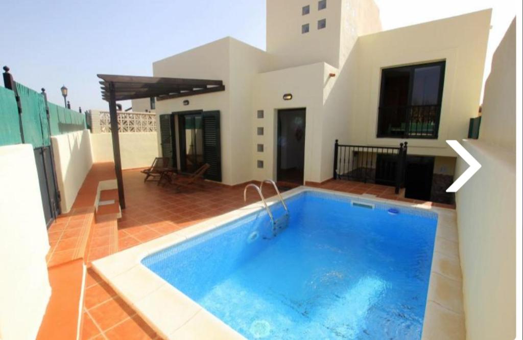 a swimming pool in the middle of a house at Villa con piscina, vistas, dunas, mar, 6 personas in Corralejo