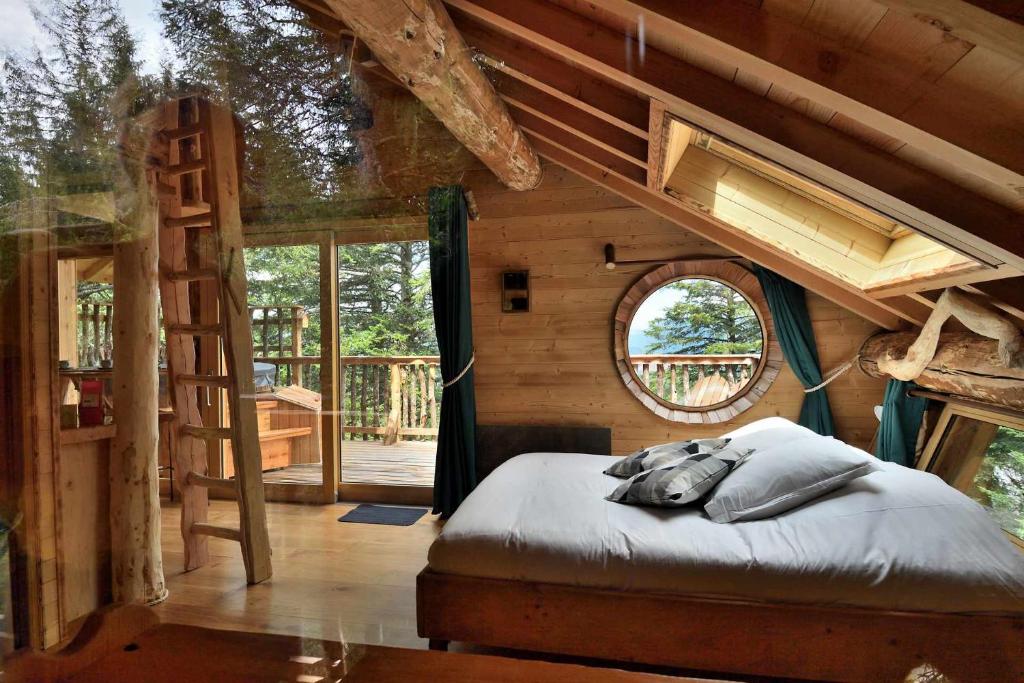a bedroom in a tree house with a bed and a ladder at Cabanes des Volcans in La Tour-dʼAuvergne