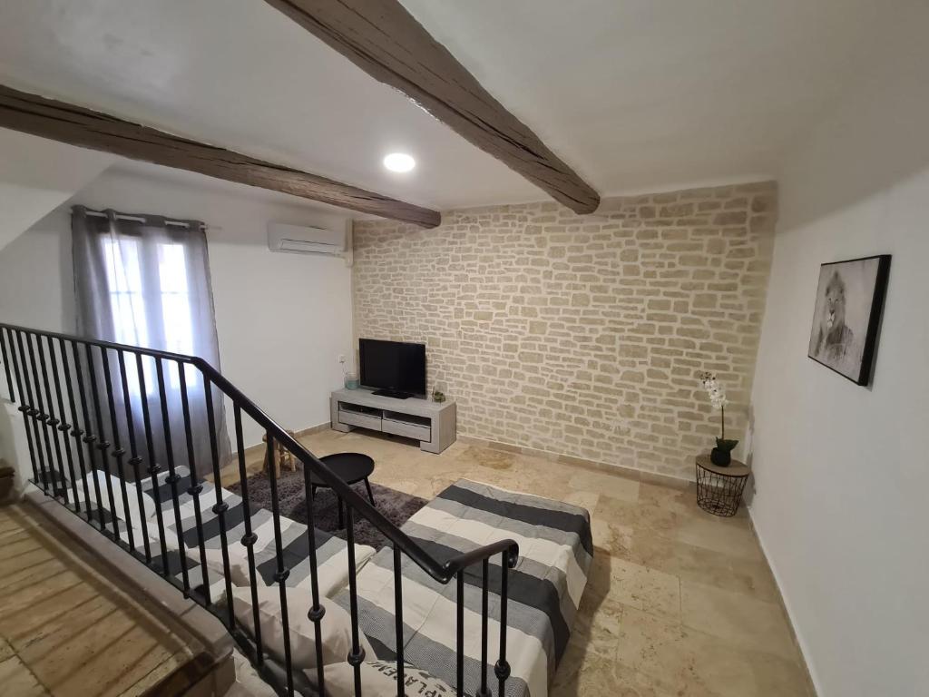 a living room with a staircase and a brick wall at Maison centre ville avec accueil hôte in Manosque