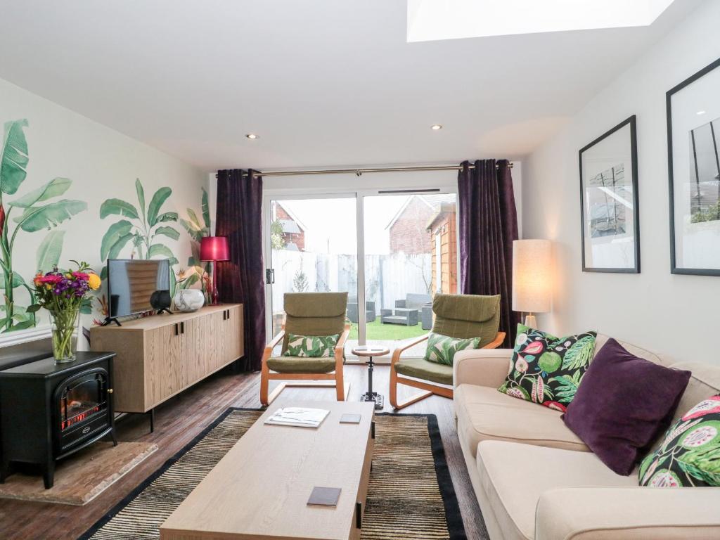 a living room with a couch and a tv at Tile Cottage in Lymington