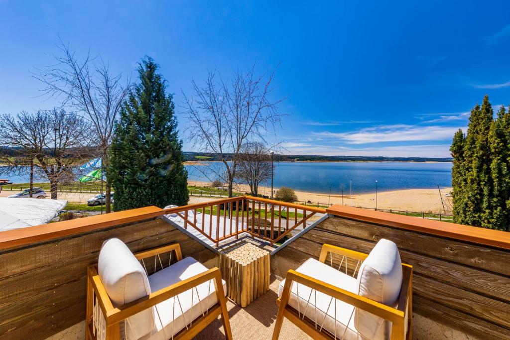 a balcony with two chairs and a view of a lake at Les Terrasses Du Lac in Langogne