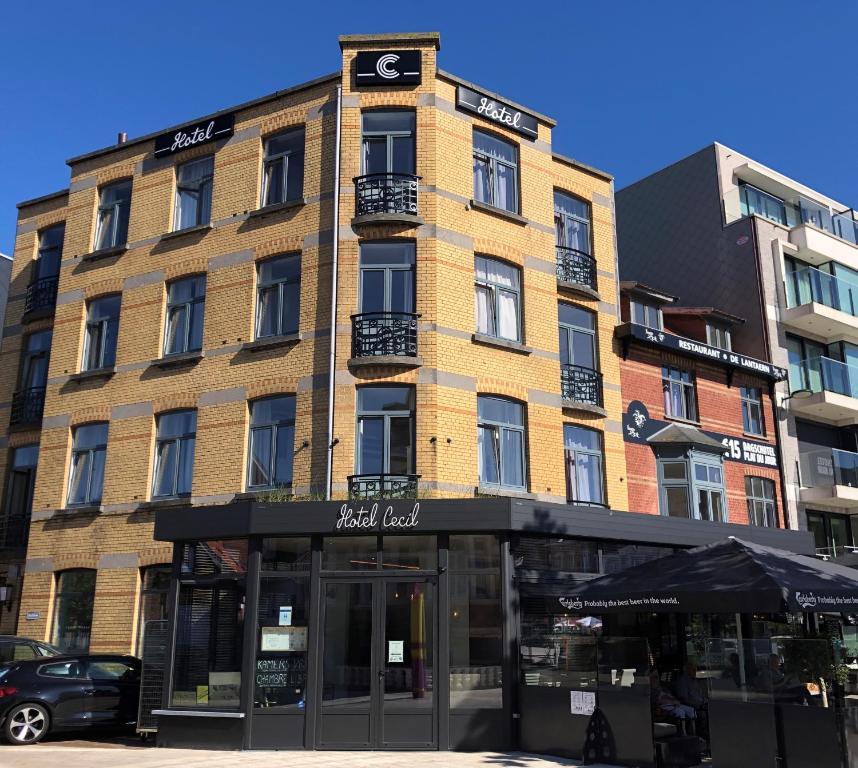 Un grand bâtiment avec un panneau en haut dans l'établissement Hotel Cecil, à La Panne