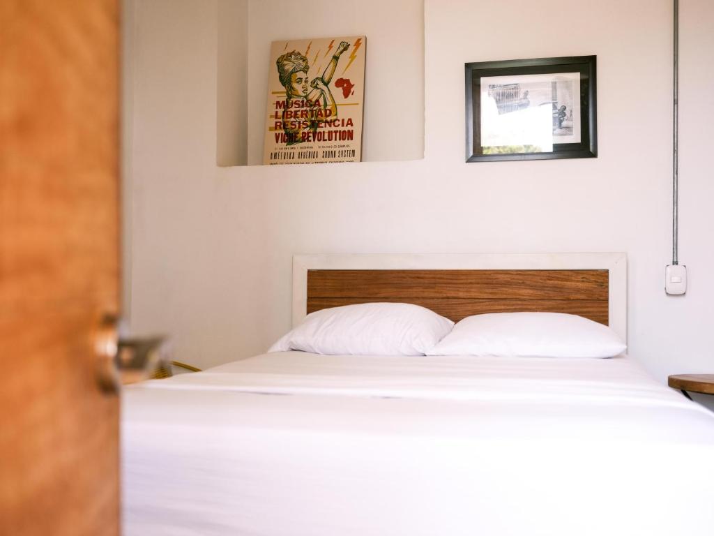 a bedroom with a white bed with two posters on the wall at Casa Tunido in Santa Marta