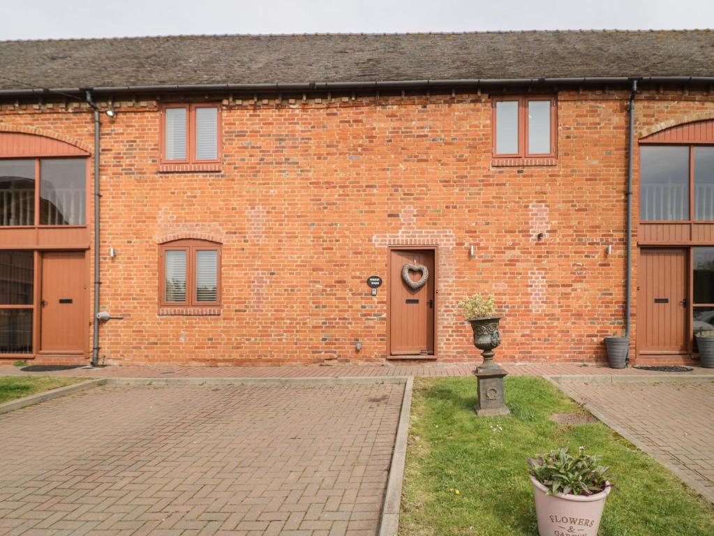 a brick building with a door and a courtyard at The Wheat House in Stratford-upon-Avon