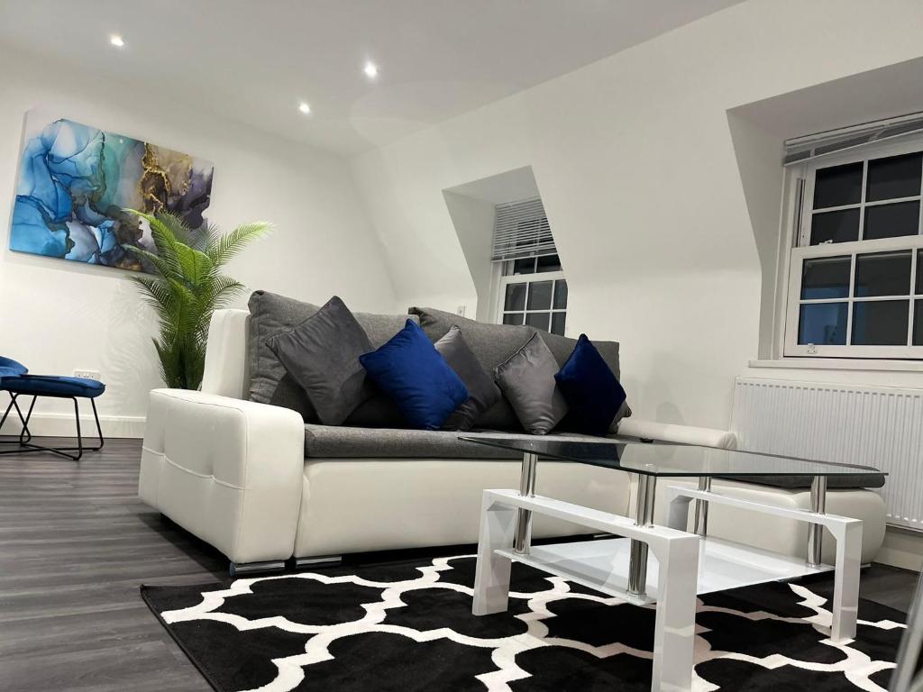 SPACIOUS & MODERN 1 bed CITY CENTRE Apartment في واتفورد: غرفة معيشة مع أريكة بيضاء وطاولة زجاجية