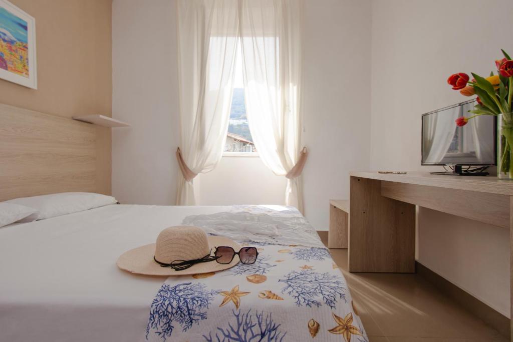 Un dormitorio con una cama con sombrero y gafas de sol. en Hotel Stella Maris Terme en Isquia