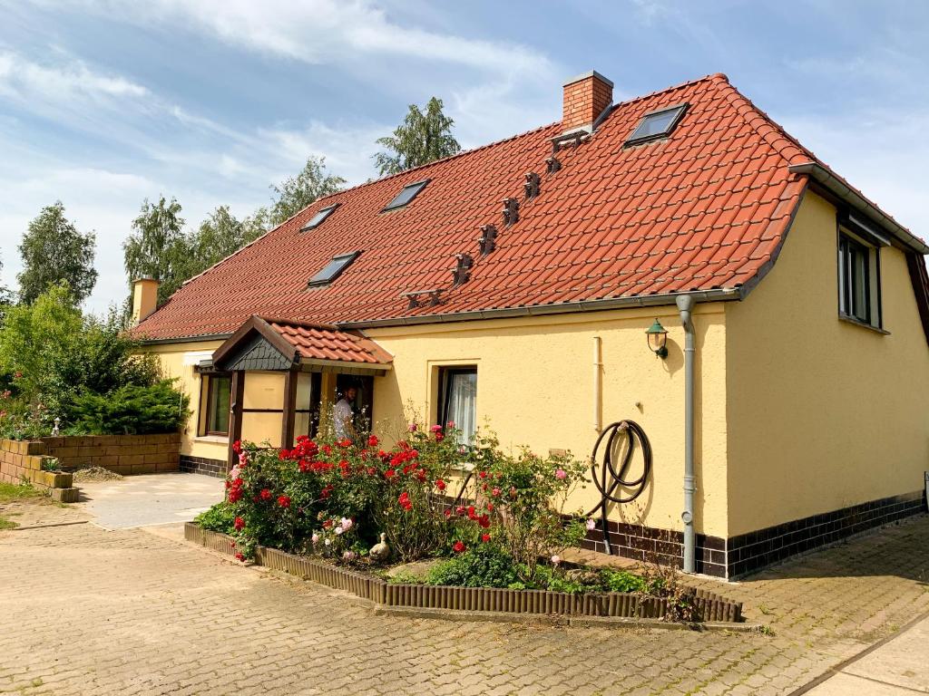 a yellow house with a red roof and some flowers at Ferienwohnung Schulz Mönchhagen - Erdgeschoss in Mönchhagen