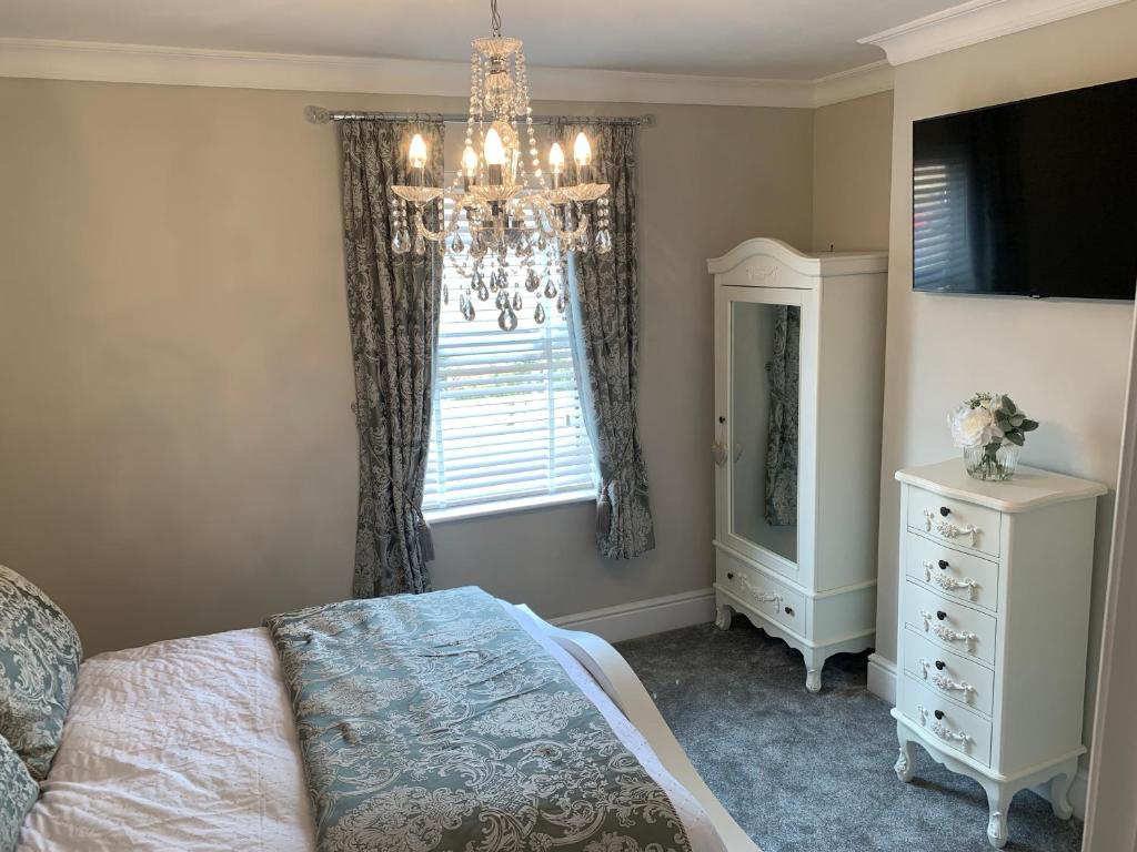 1 dormitorio con lámpara de araña, cama y ventana en Luxury House, central Stamford with parking, en Stamford