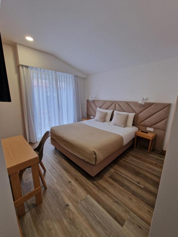 a hotel room with a bed and a desk and a window at Soldouro Train Suites in Aveiro