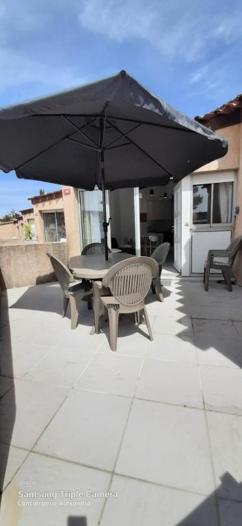 een tafel en stoelen onder een parasol op een patio bij Jardins de Neptune - villa en résidence avec piscine in Saint-Cyprien