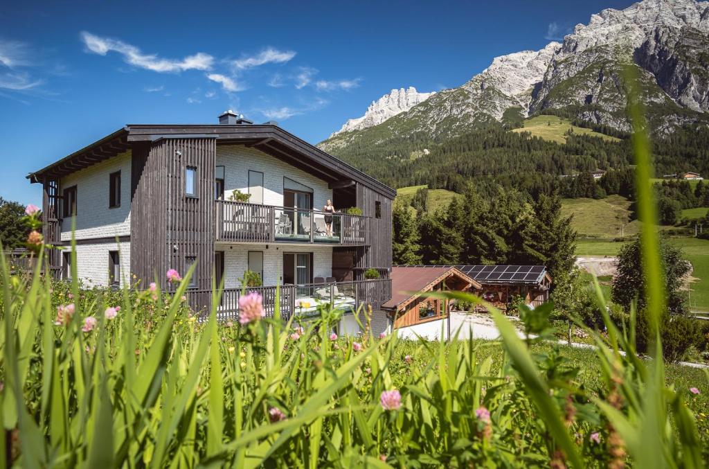 a house in the mountains with flowers in the foreground at Apart Herzog - Design Apartments Leogang direkt an der Steinbergbahn und -piste in Leogang