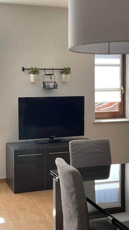 a living room with a tv and a table with a chair at Appartamento Palazzo dei Duchi in Avigliana