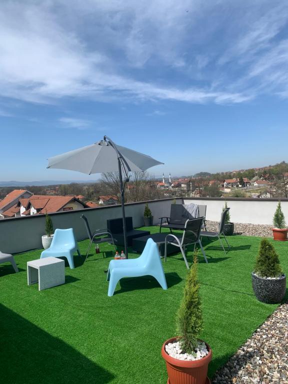a patio with chairs and an umbrella on the grass at Apartmani Imamovic in Dubrave Gornje