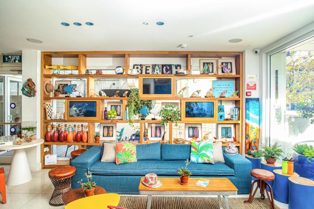 a living room with a blue couch and wooden shelves at Yam Hotel - an Atlas Boutique Hotel in Tel Aviv