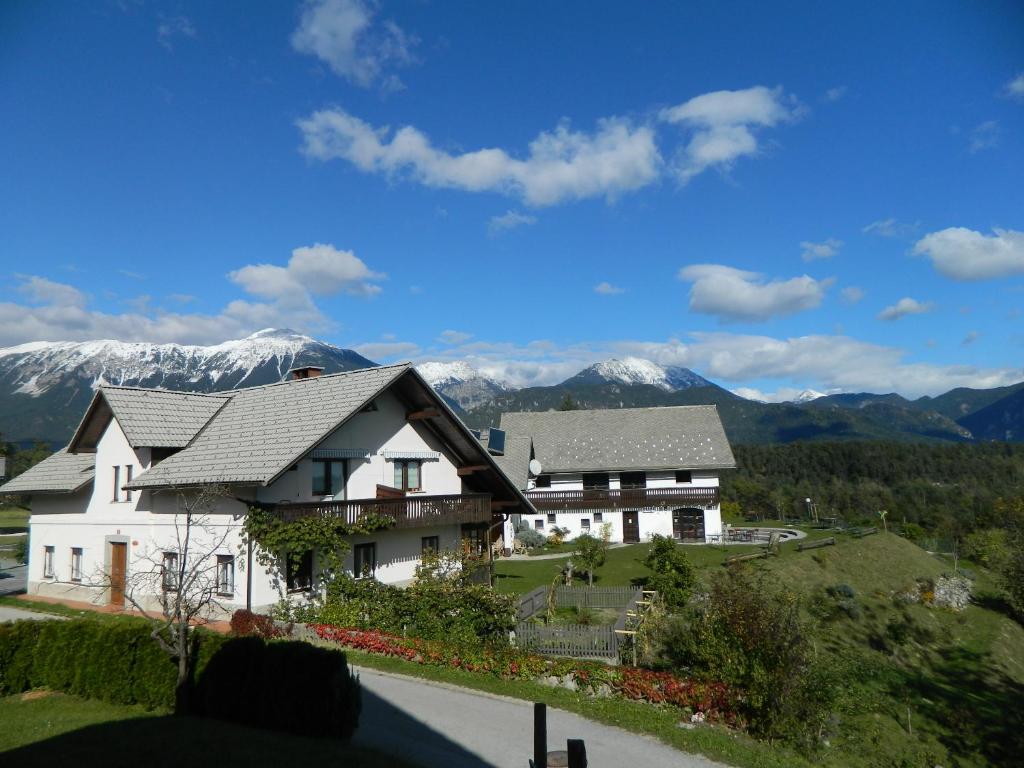 a large white house with mountains in the background at Apartma BioFit Bled in Bled