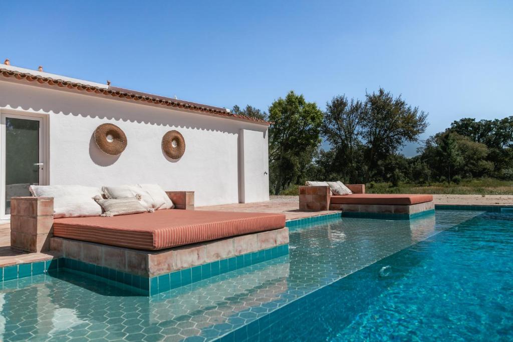 Una cama está sentada junto a una piscina en Alto en Alcácer do Sal